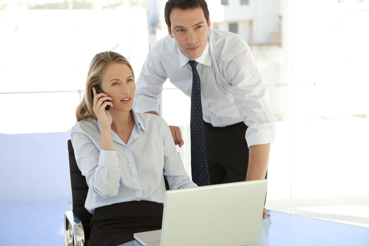 Business training - Manager coaching young businesswoman on the phone at workplace